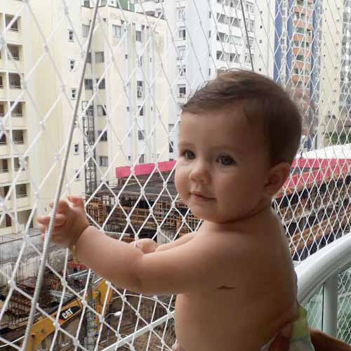 Bebê protegido por rede de proteção resistente na varanda